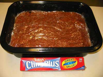 Pack the meat into a plastic or enameled container. Do not use metal. It will give a metalic flavor to the jerky. Push it all down to remove all the air pockets and cover with plastic wrap. Iwill place this batch in the fridg. overnight.